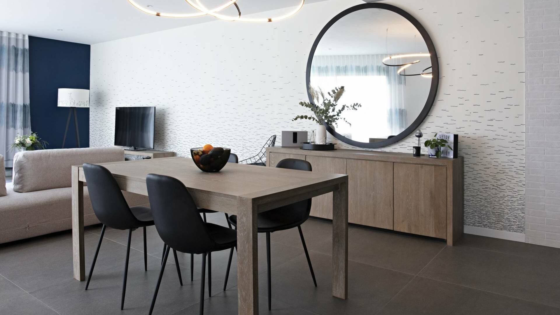 Décoration et agencement d'une maison sur plans à Bédée - séjour avec meubles en bois, chaises, suspension et miroir XXL noirs